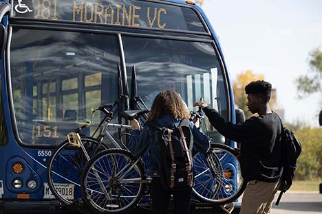 Image of a male student helping a female student to load bike on rack.