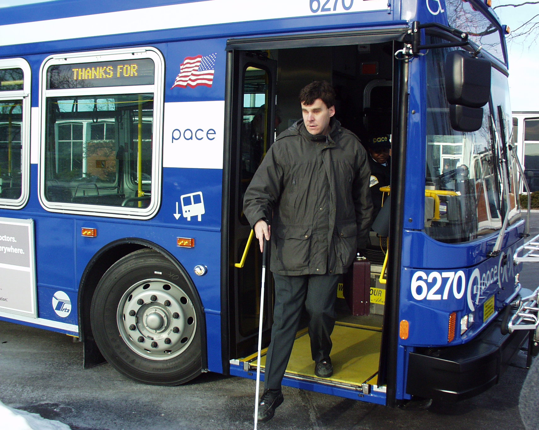 rider with white cane exiting bus