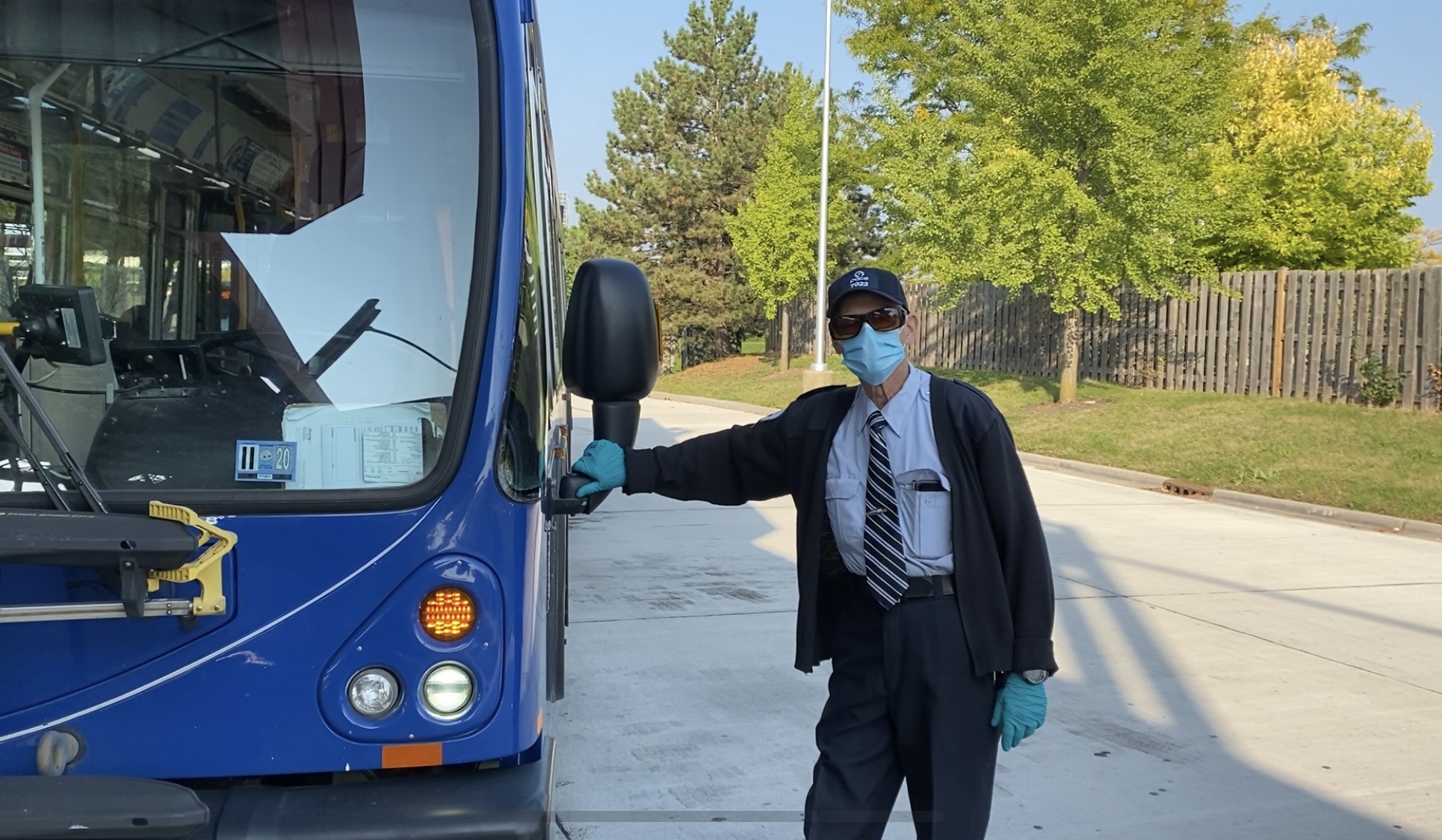 Image showing a masked Pace bus operator stands by a Pace bus