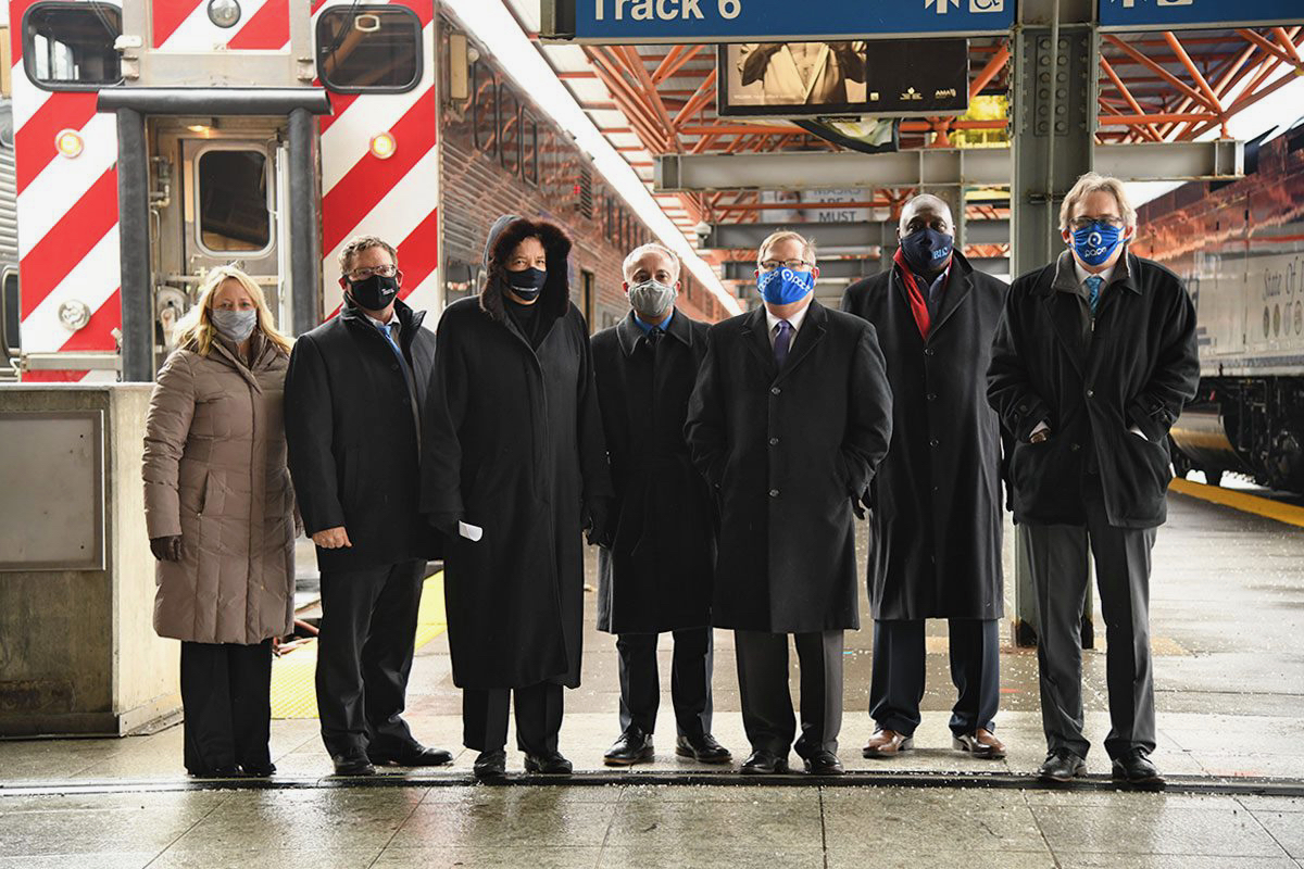 Image showing seven people stand in front of metro trains with mask on for Fair Transit South Cook Launch