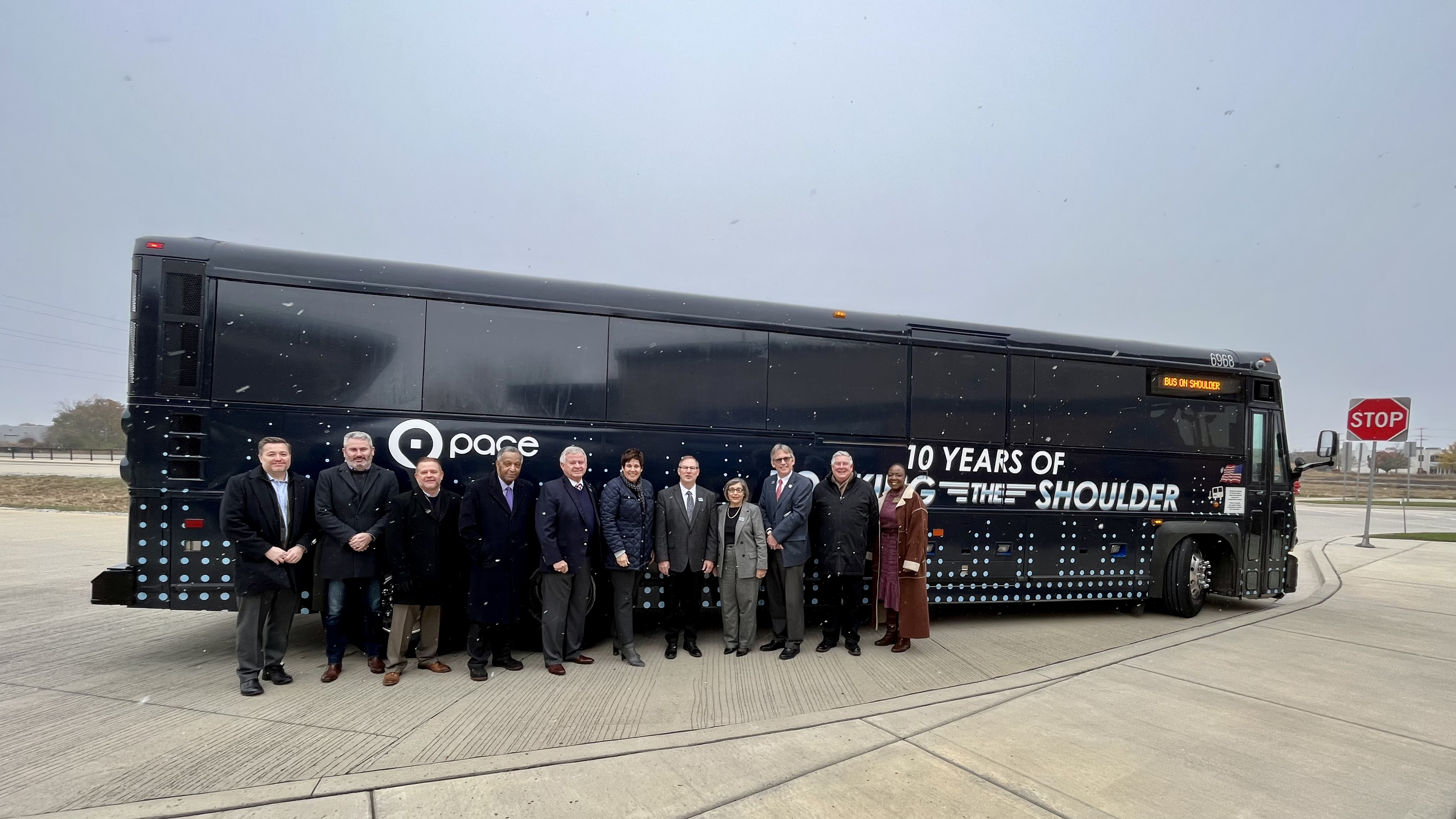 Image showing officials stand in front of a Pace Bus with words 10 Year of Rocking the Shoulder on it