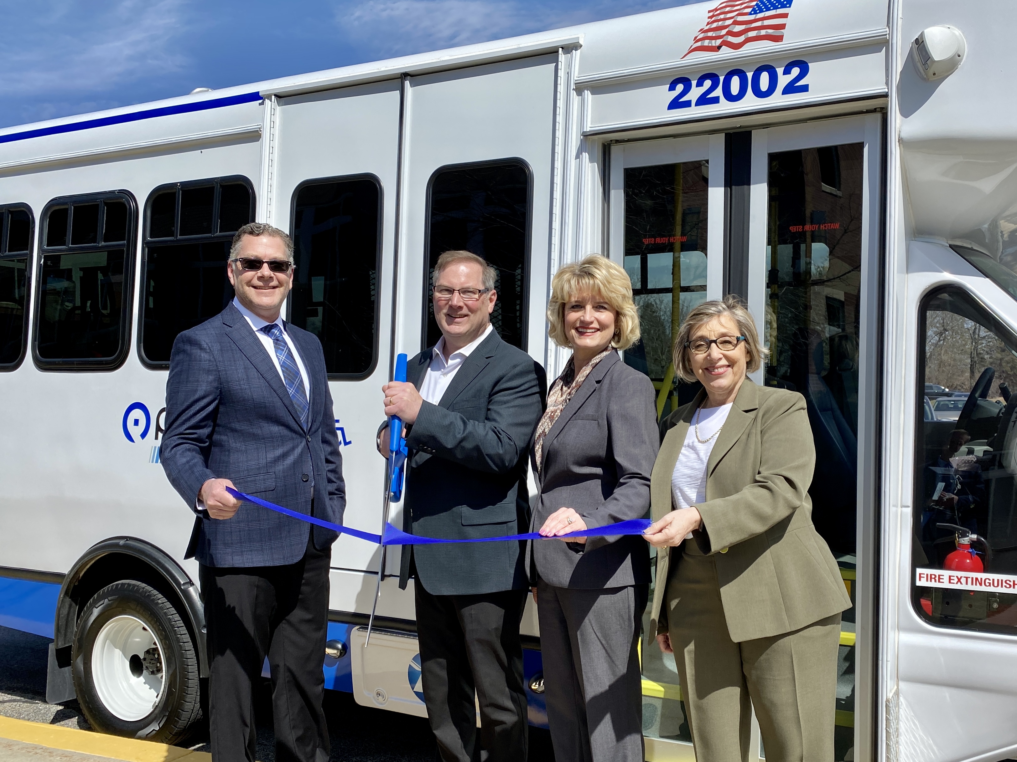 Image showing four officials stand in front of a MCRide bus cutting a blue ribbon 