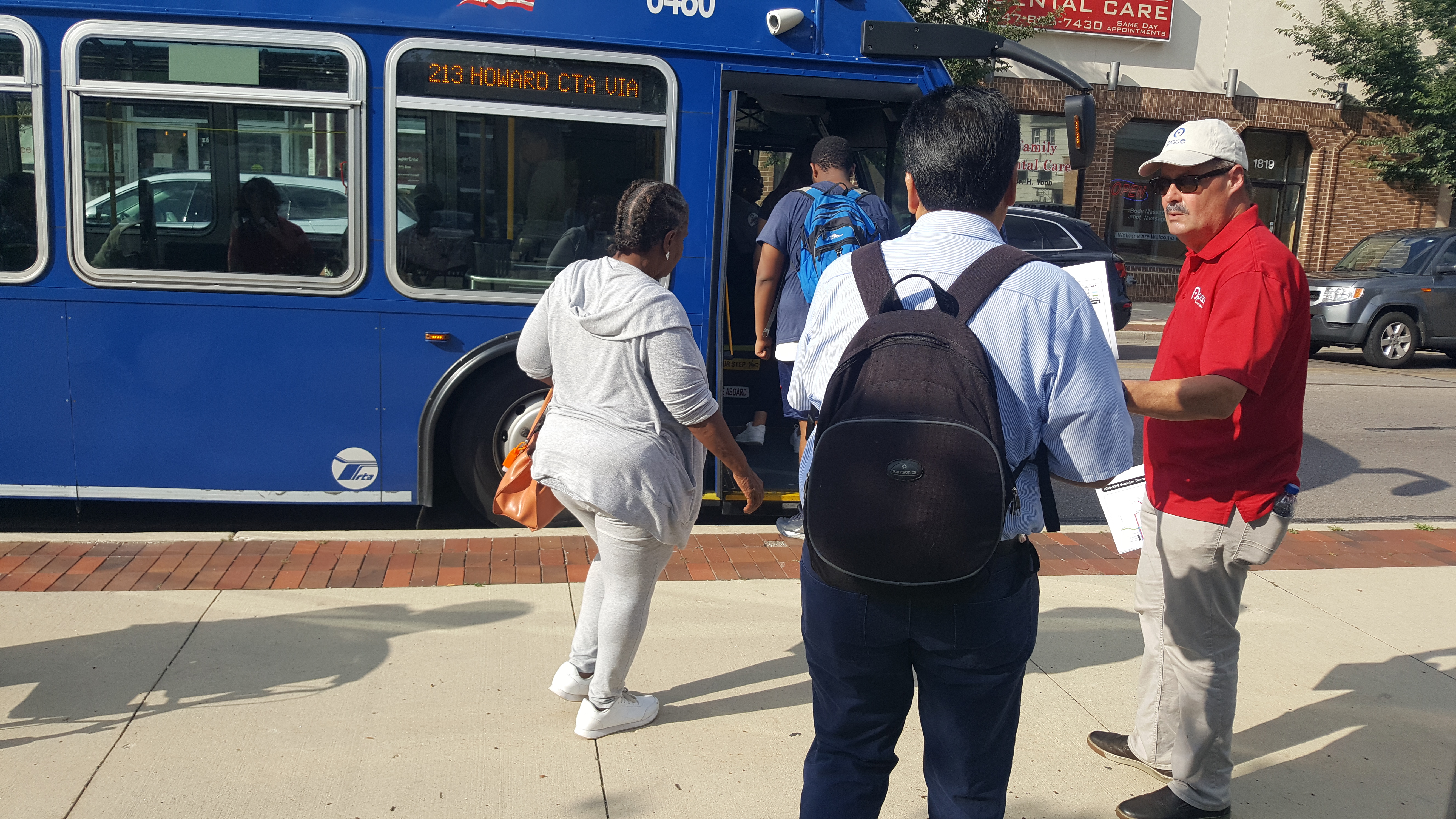 Pace employee hands an updated schedule to a rider boarding a route 213 bus