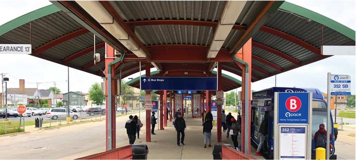 An image of Pace's Harvey Transportation Center. The image shows the covered waiting area flanked by bus bays. 