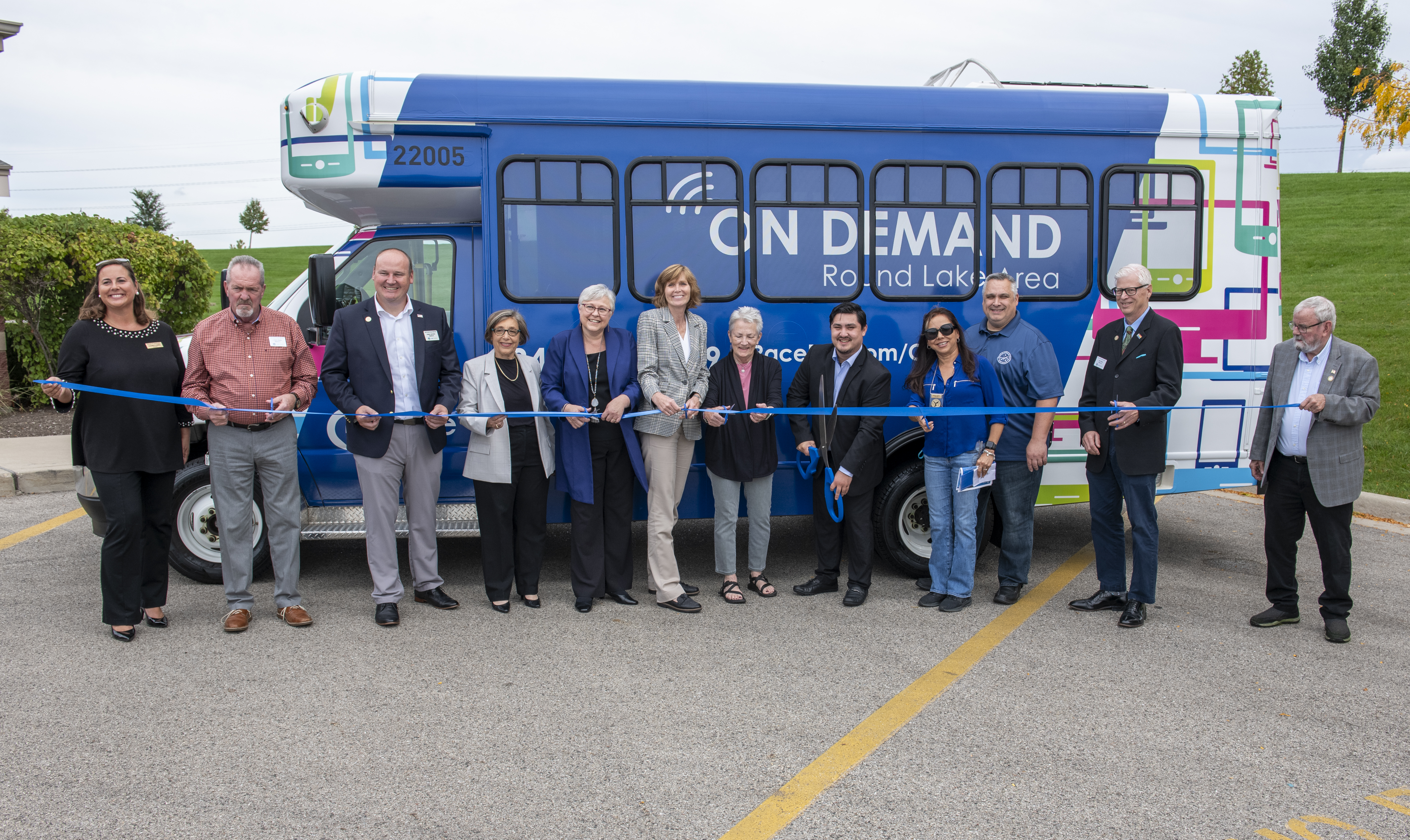 Officials pose for a ribbon cutting in front of the Pace Round Lake Area On Demand bus. 