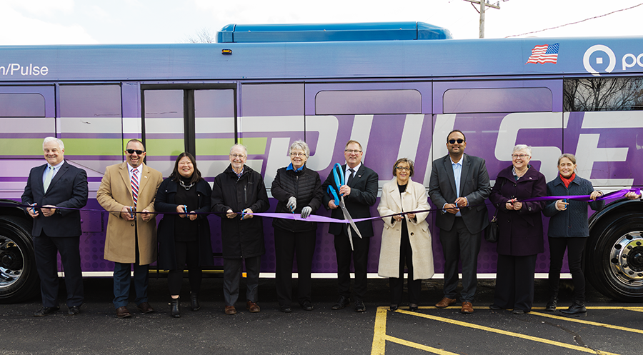 Photo of officials cutting a purple ribbon in front of a Pulse bus. L-R: Pace Director Chris Canning; Pace Director David Guerin; Cook County Commissioner Josina Morita; Skokie Mayor George Van Dusen; Cook County Commissioner Maggie Trevor; Pace Chairman Rick Kwasneski; Pace Executive Director Melinda Metzger; Senator Ram Villivalam; Pace Director Linda Soto; Representative Michelle Mussman.