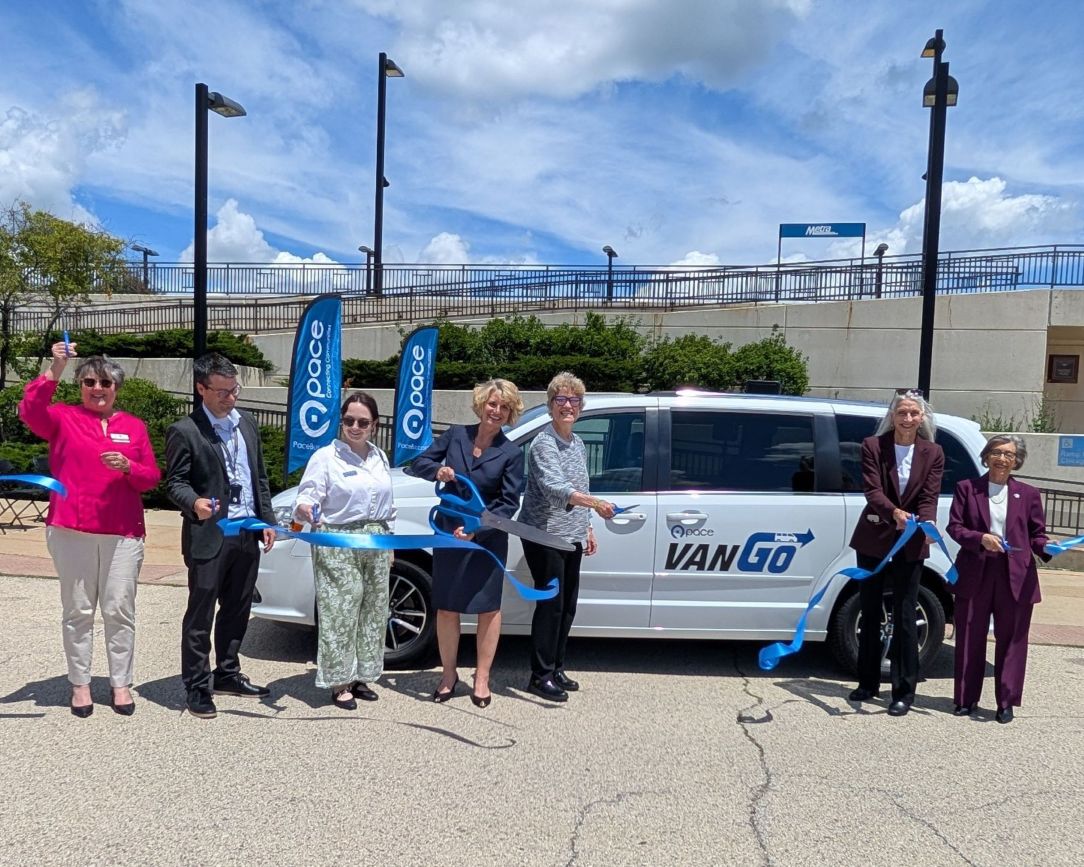 Photo of Pace leaders with officials in Crystal Lake and McHenry cutting a blue ribbon while standing in front of a Pace VanGo van.