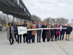 a Group of people posing in front of an electric bus charging station